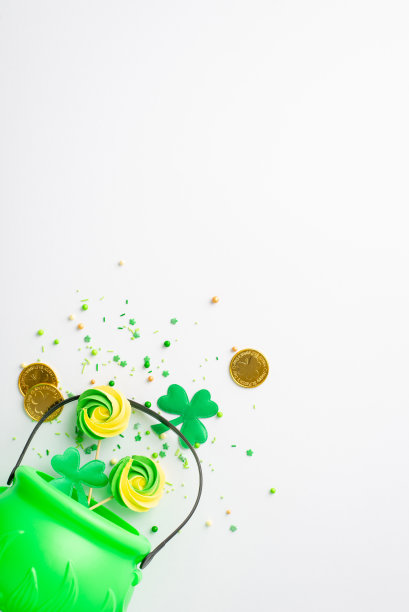 圣帕特里克节的概念。俯视图垂直照片的绿色锅蛋白糖棒棒糖洒金币和三叶草孤立的白色背景与复制空间图片下载
