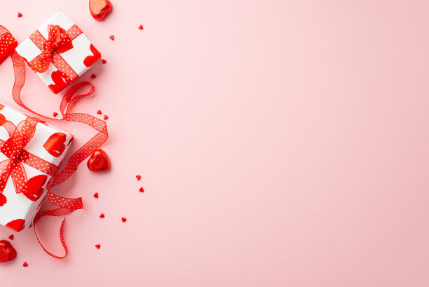 情人节的概念。顶部视图照片的礼物盒丝带心形糖果和洒在孤立的浅粉色背景与空白图片下载