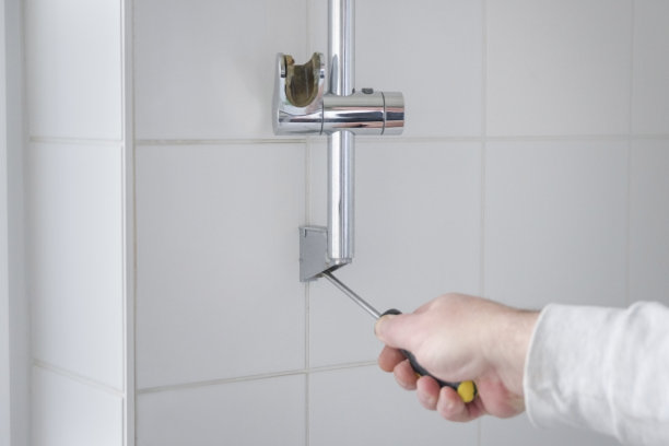 拆下墙上的螺丝，更换浴室墙上的淋浴架。图片下载