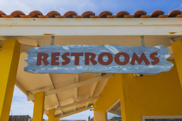 黄色建筑屋顶下厕所标志的特写。阿鲁巴岛。图片下载