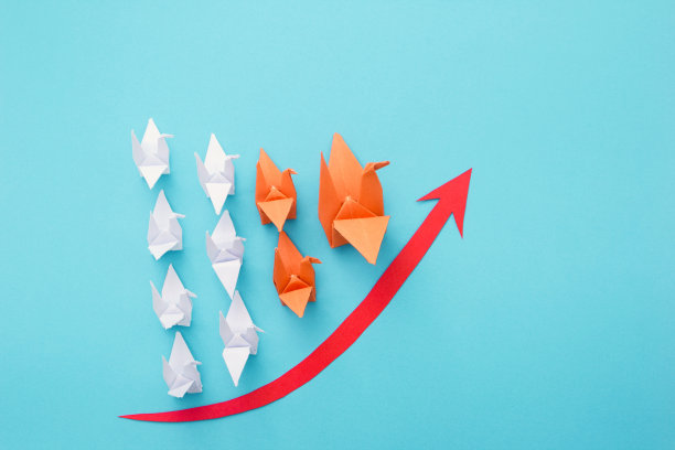 白色的鸟折叠纸组跟随橙色领导者在蓝色背景。图片下载