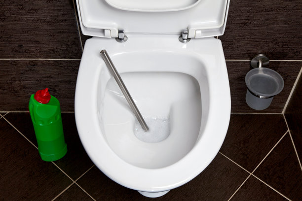 一个马桶，马桶刷，清洁剂和消毒剂在深色瓷砖背景上图片下载
