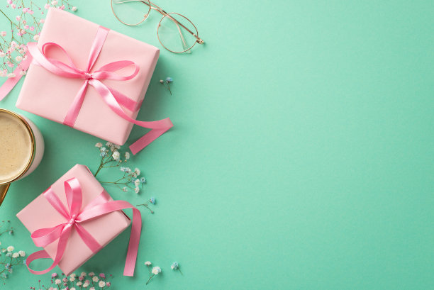 情人节的概念。顶部视图照片粉红色礼盒带蝴蝶结杯咖啡杯和吉卜草花孤立的蓝绿色背景与空白图片下载
