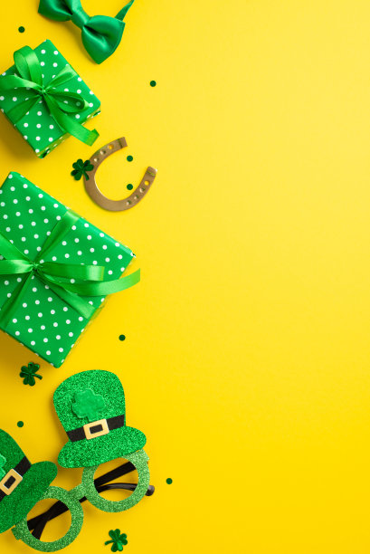 圣帕特里克节的概念。俯视图垂直照片绿色礼盒马蹄形帽子形状的聚会眼镜蝴蝶结和三叶草形状的五彩纸屑孤立的黄色背景与空白图片下载