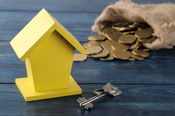 钥匙和黄色装饰的房子和钱在背景上的蓝色木桌。置业概念图片下载
