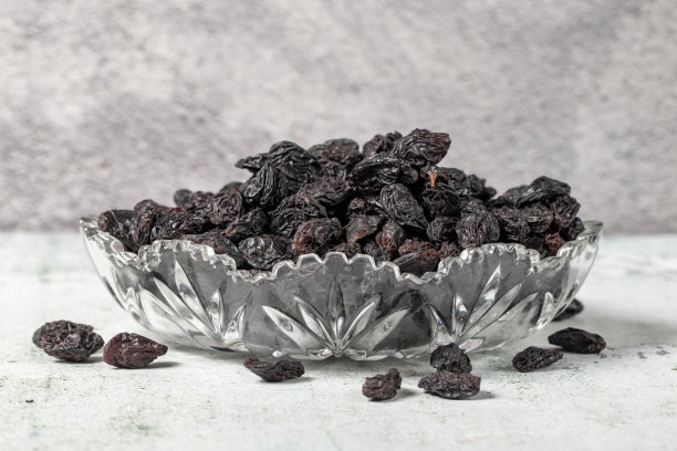 石头背景上的黑葡萄干。玻璃碗里的葡萄干。坚果品种。健康饮食。近距离图片下载