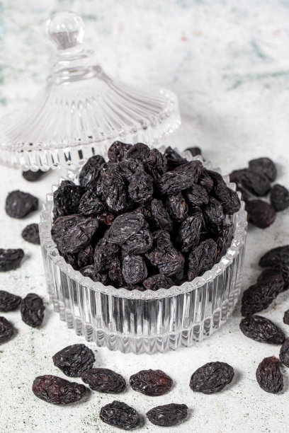 石头背景上的黑葡萄干。玻璃碗里的葡萄干。坚果品种。健康饮食。近距离图片下载