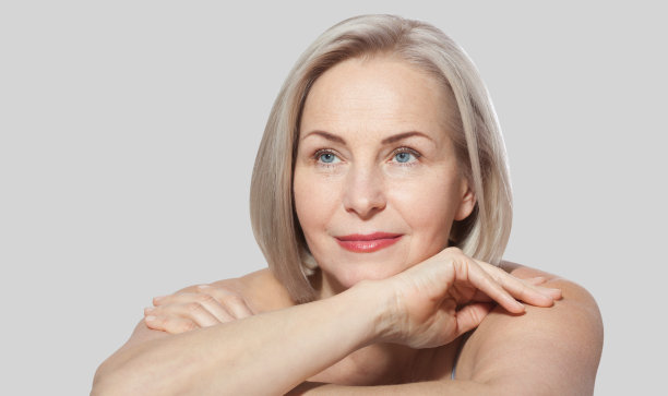五十岁的女人非常满意她精心打扮的脸放松地看着相机。宏的脸。现实的图像与他们自己的不完美。灰色隔离。图片下载