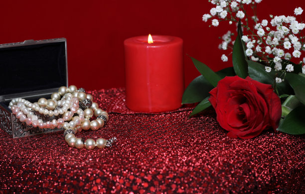 红丝绒背景的蜡烛和香水玫瑰图片下载