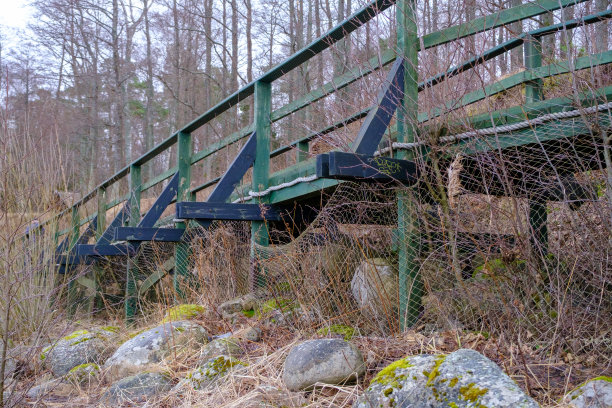 近距离照片的木质走道地板，人行天桥栏杆制成的木板涂成绿色。边缘铺着渔网和岩石图片下载