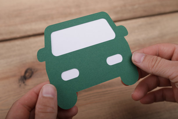 特写的手拿着一个纸板绿色汽车，上面的木制表面图片下载