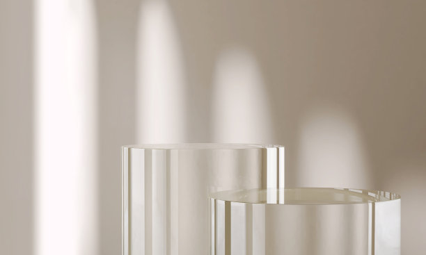 两个圆形、圆柱形的透明玻璃平台在不同程度的拱形阳光下，米黄色墙壁背景上窗户的阴影图片下载