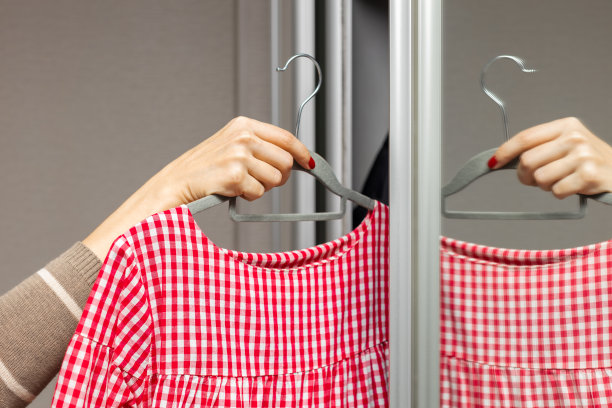 一个女人从衣柜里拿出一件红裙子。图片下载