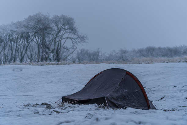 帐篷在冬天的条件下，覆盖着雪和冰的海滩与森林和雾的背景图片下载