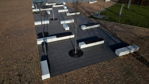 白色混凝土长凳和波浪形状的公园在一个黑暗的鹅卵石广场上，干净的混凝土表面灰棕色白色行人和休息区在滑板公园的年轻人，以上青少年图片下载