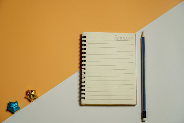 在头顶上接近平平视图清晰螺旋教科书的照片与铅笔画在一个橙色的一半分裂和白色的桌子。图片下载