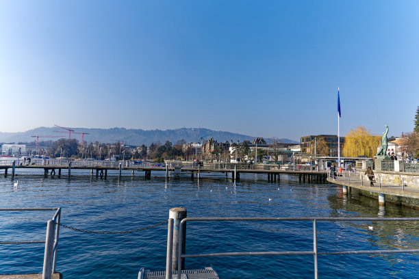 Scenic view of quayside at lake shore of Lake Zürich with people walking at City of Zürich on a sunny winter day.图片下载