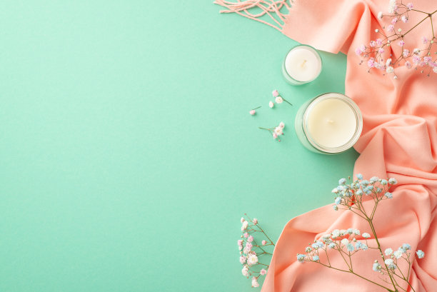 你好，春天概念。顶部视图照片蜡烛在玻璃支架蓝色和粉红色的吉卜草花和软围巾孤立的蓝绿色背景与空白图片下载