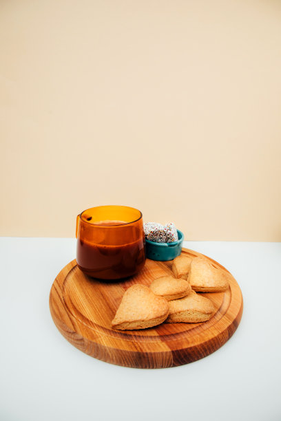 一杯有泡沫的咖啡和一个白底心形酥饼的盘子图片下载