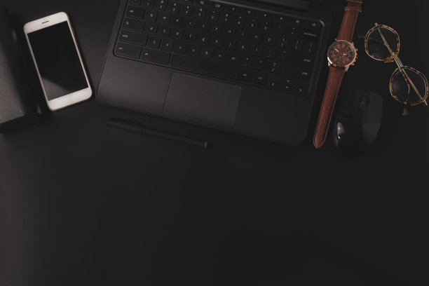 俯视图暗镜头的智能手机，太阳镜，手表附近的笔记本电脑在桌子上图片下载