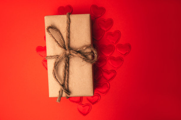 礼物用棕色纸包在红色缎子的心形上。情人节瑞布背景。有选择性的重点图片下载