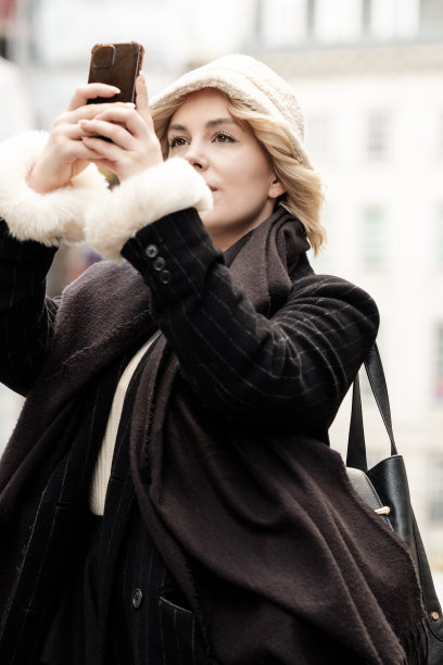 一位年轻的金发女子在伦敦的一条街上用手机拍照。图片下载