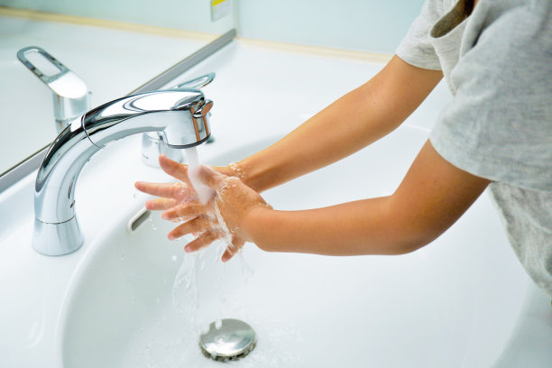 穿着短袖的孩子的手，在明亮的白色脸盆里用水龙头冲洗双手图片下载