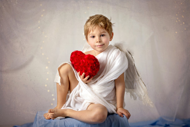 小丘比特蹒跚学步的男孩，拿着弓箭，美丽的金发小天使图片下载