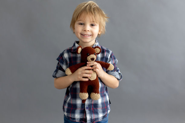 小蹒跚学步的孩子，金发男孩，玩手工编织的小玩具图片下载