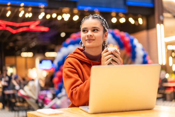 欢快漂亮的白种人女士与辫子有一些咖啡坐在她的笔记本电脑前图片下载