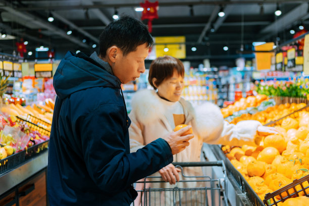一对中年夫妇在超市挑选新鲜的橙子和有机水果，这是健康的生活方式图片下载