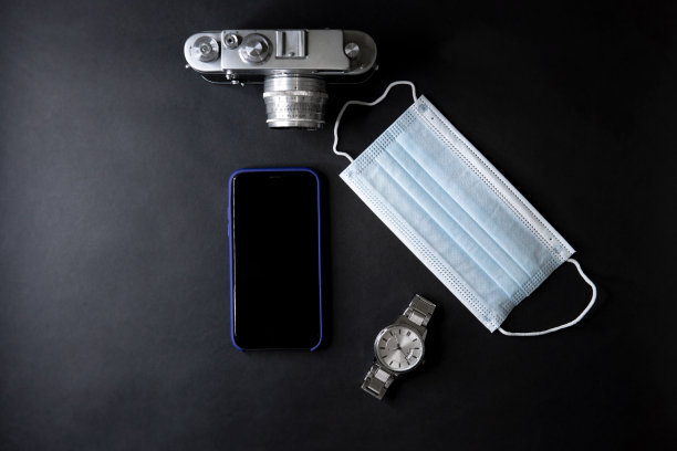 黑色背景上的智能手机、医用口罩、手表和相机的俯视图图片下载