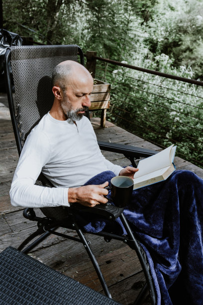 拉丁美洲的墨西哥，一名西班牙男子早上在一座乡村别墅的露台上拿着咖啡杯看书图片下载