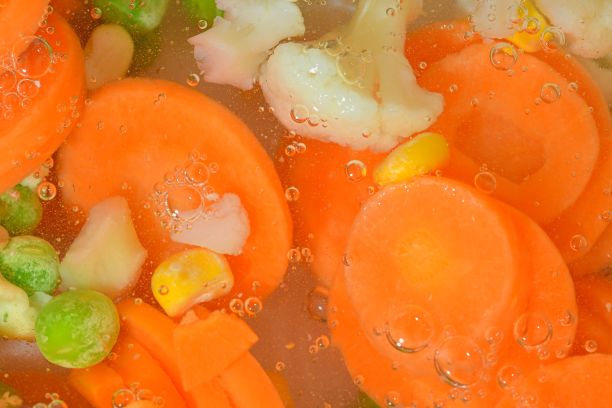 特写新鲜蔬菜汤与胡萝卜，豌豆，花椰菜和玉米在白色背景。白底白水，用胡萝卜、豌豆、花椰菜和玉米煮蔬菜，特写。水平的形象。俯视图，平面设计图片下载