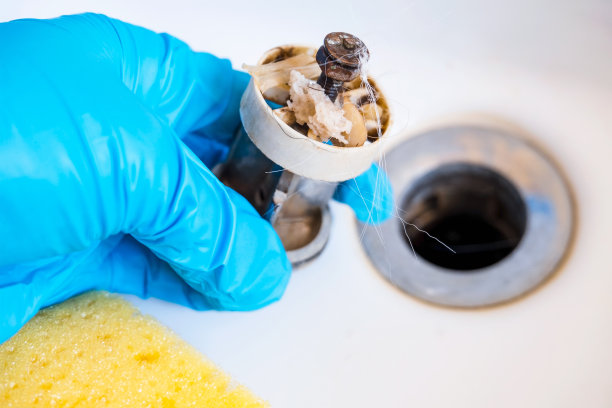 浴室排水盖上有头发和垃圾。堵塞滤网与毛发隔离的白色背景。清洗浴塞孔图片下载