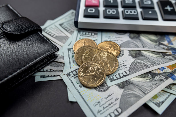 黑色皮革钱包与各种面额的美元计算器在黑色背景图片下载