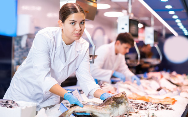积极的女售货员在鱼店里拿着鳕鱼图片下载
