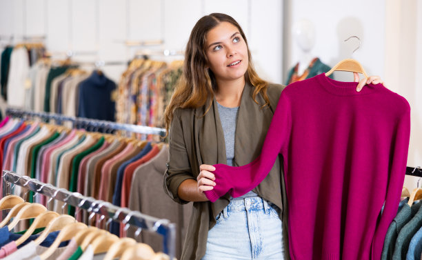 年轻女子在商店选择针织毛衣图片下载