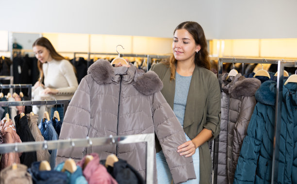 梦幻的女性在服装店购物时选择温暖的冬季夹克图片下载