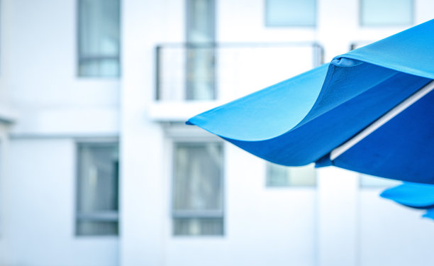 蓝色泳池伞与酒店背景。图片下载