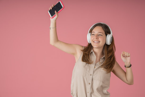 快乐的年轻女士一边听音乐一边跳舞图片下载