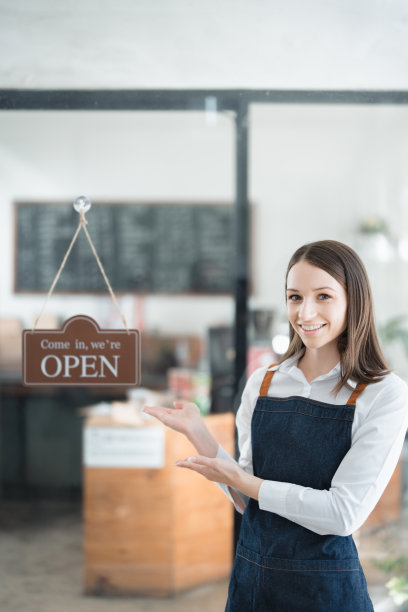 在咖啡店吧台前，一名年轻的亚裔女性正在创业，她系着围裙，露出笑容。企业主，餐厅，咖啡师，咖啡馆，网上中小企业图片下载