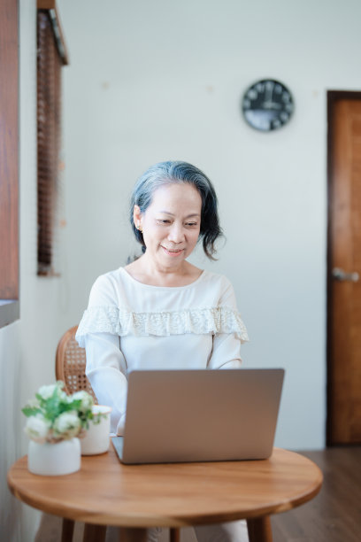 一位年长的亚洲妇女在电脑上工作的现代姿势的肖像。图片下载