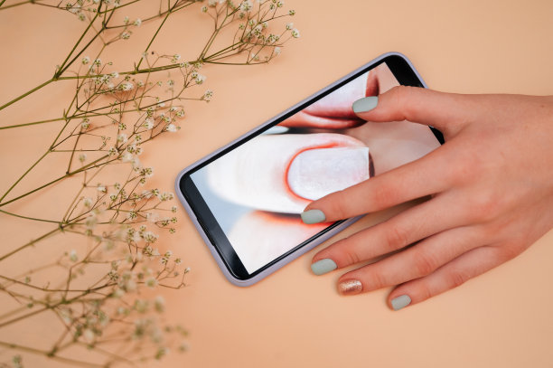 一个女美甲师用手机的特写，显示她的指甲在显示屏上。图片下载