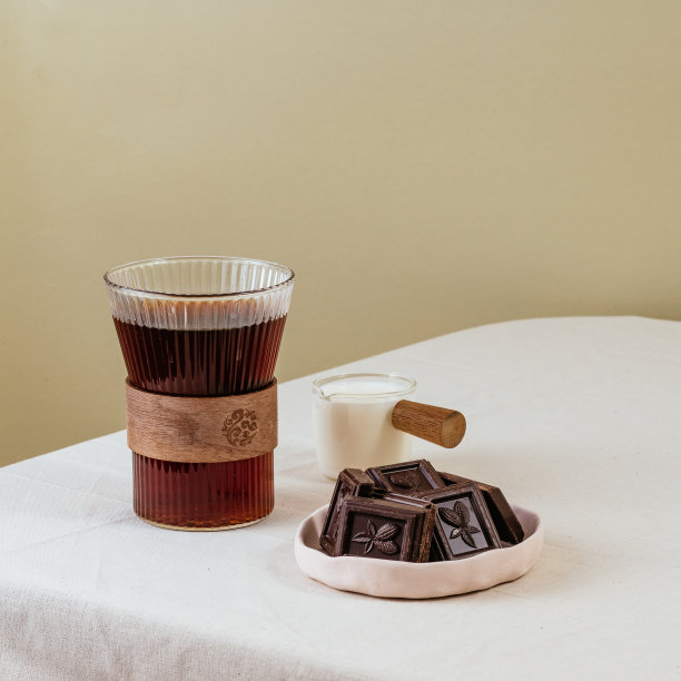 咖啡装在桌上的透明杯子里，牛奶装在牛奶壶里，巧克力装在盘子里。图片下载