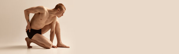 男性的审美。年轻的红发男孩穿着黑色内衣，四角裤在灰色的工作室背景下摆姿势。运动型身材。男性的健康、美容和运动生活方式图片下载