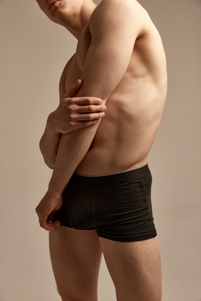 裁剪图像的运动，肌肉的身体在黑色内衣。男模特在灰色的工作室背景上摆姿势。男性的健康、美容和运动生活方式图片下载