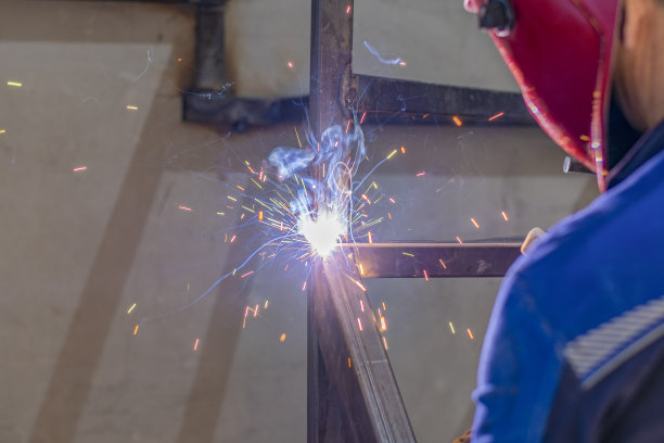 一名焊工正在用焊机组装一幢居民楼的金属楼梯结构。图片下载