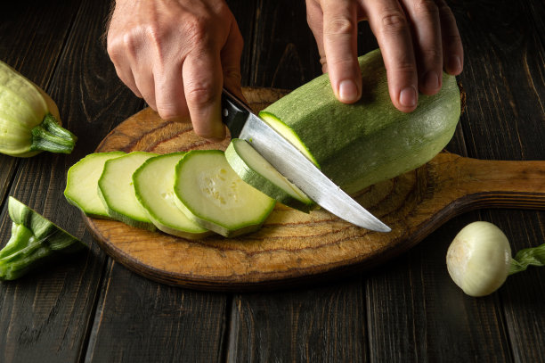 厨师用刀在木砧板上切西葫芦，准备美味的食物图片下载