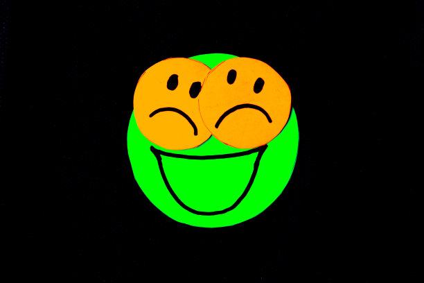 黑色背景上画有人脸的圆形剪纸。假装快乐的概念，但有问题和悲伤图片下载